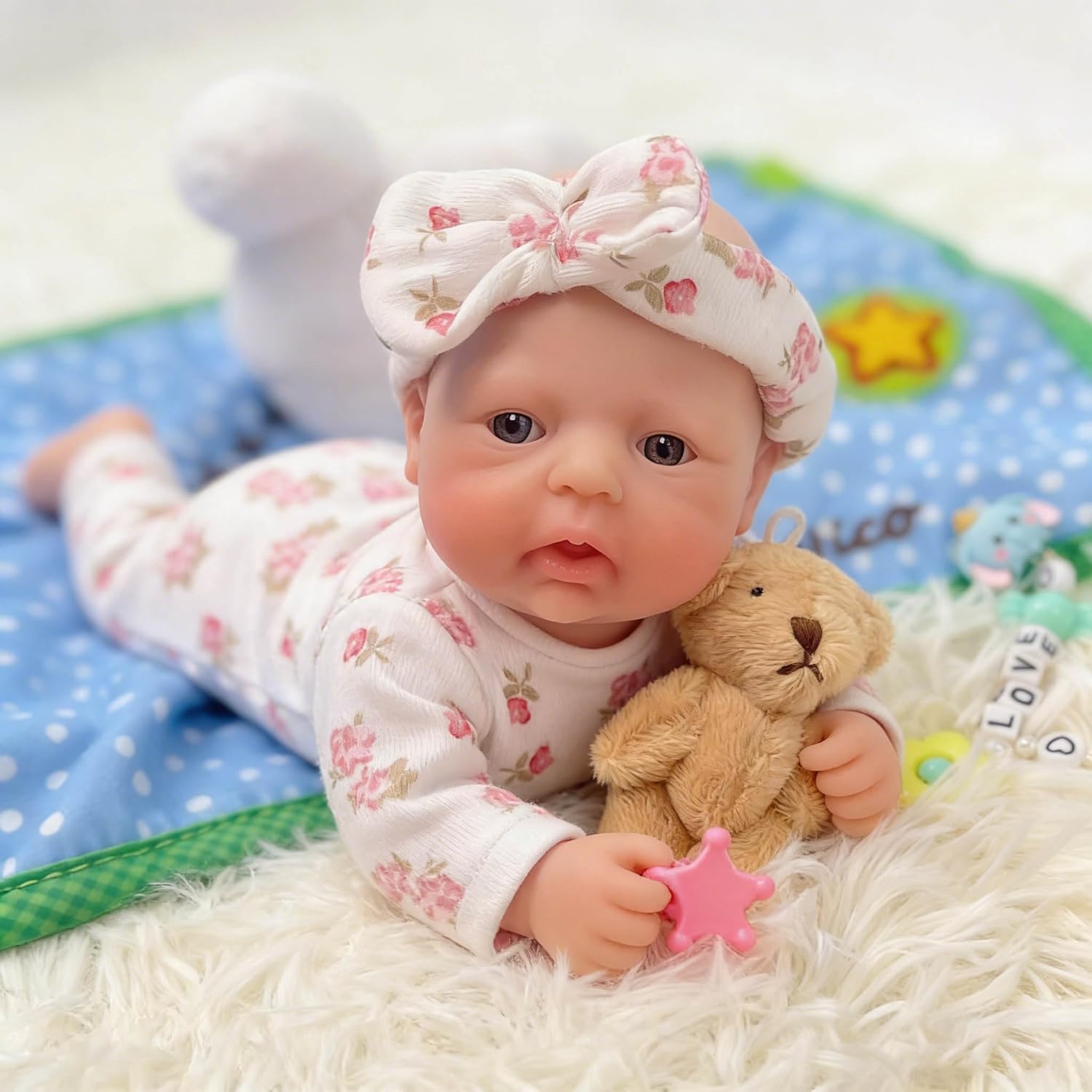 Realistic Baby Doll Travel Toy for Kids Realistic baby doll wearing floral outfit and bow headband while holding a teddy bear<br />