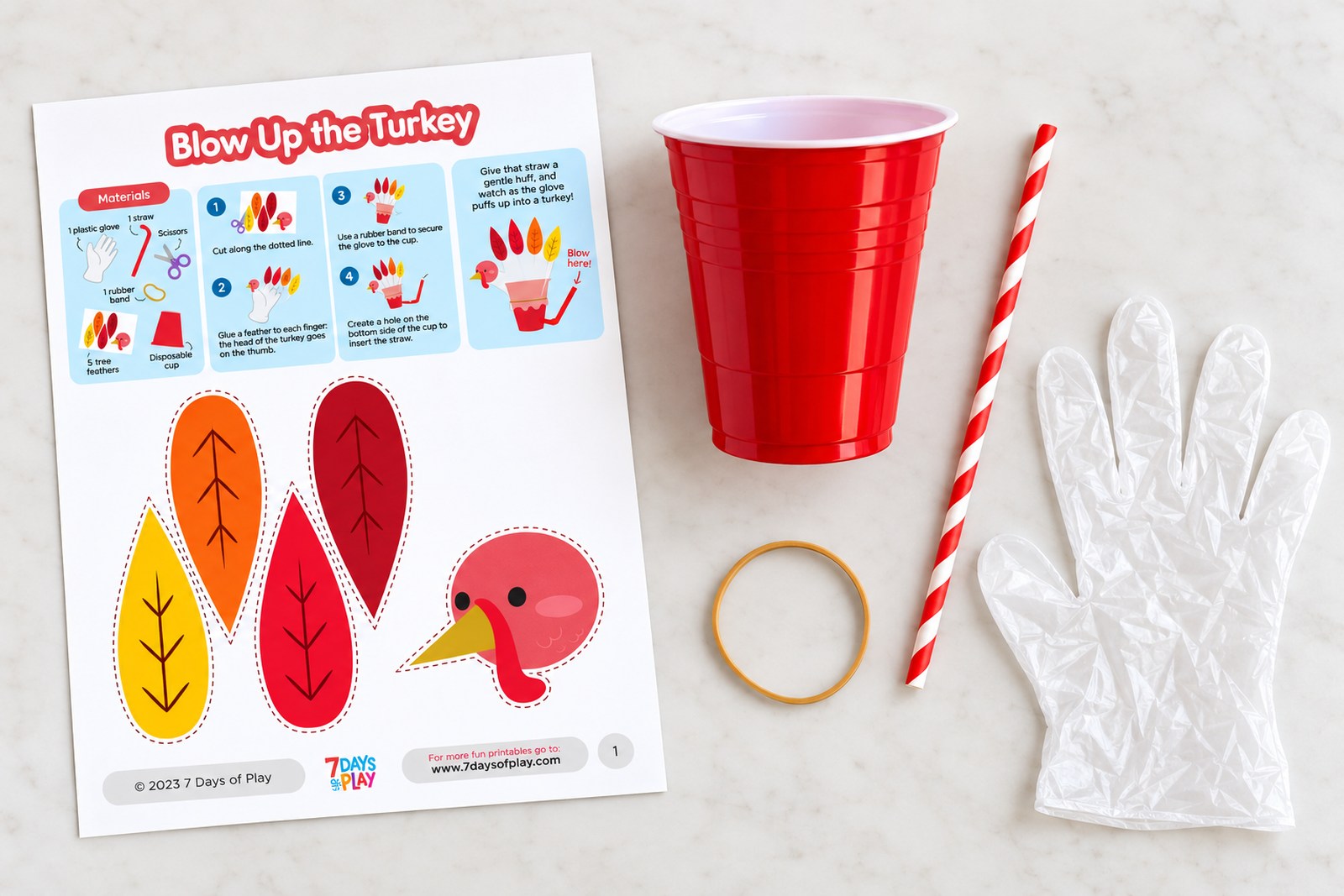 Flat lay of the blow up turkey supplies: the printable sheet with turkey head and four paper feathers, a red plastic cup, a red and white paper straw, a rubber band and a clear disposable glove