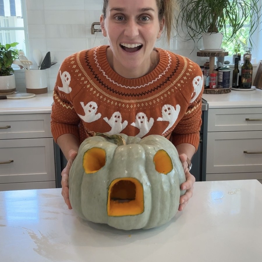 A pale green pumpkin with a door and two round windows cut into it, ready to decorate
